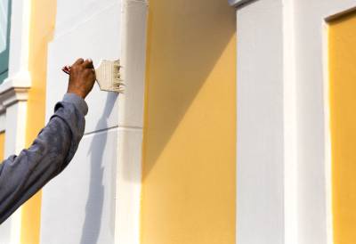 Peintre professionnel réalisant la remise en peinture d'une façade à l'aide de produits résistants aux intempéries