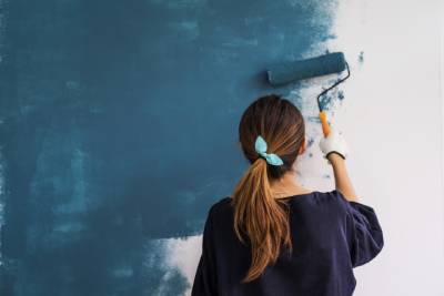 Jeune femme réalisant la peinture intérieure de son habitation.